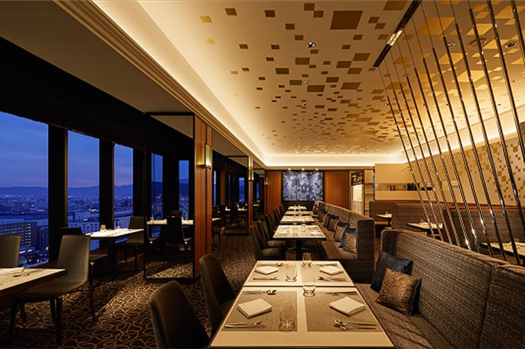 夜景を望む大きな窓とテーブル席が並ぶダイニング空間