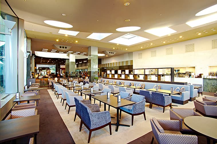 テーブルと椅子が整然と並ぶ明るく落ち着いたロビーラウンジの様子