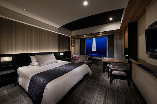 落ち着いた照明が灯る、モダンで洗練されたホテルの客室の全景。