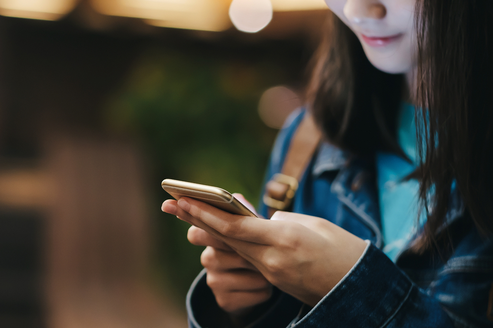 夜の街角で、スマートフォンを操作する女性のクローズアップ。