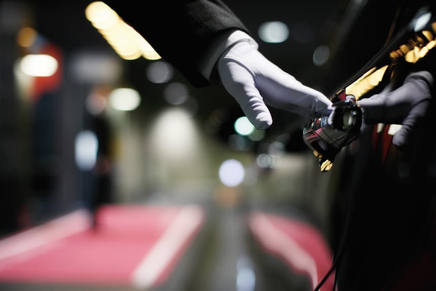 ホテルのバレットパーキング。白手袋のスタッフが車のドアを開けている。