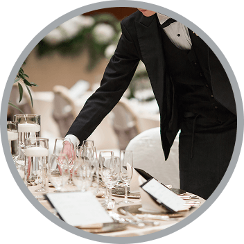 フォーマルな服装でテーブルを整えるスタッフ