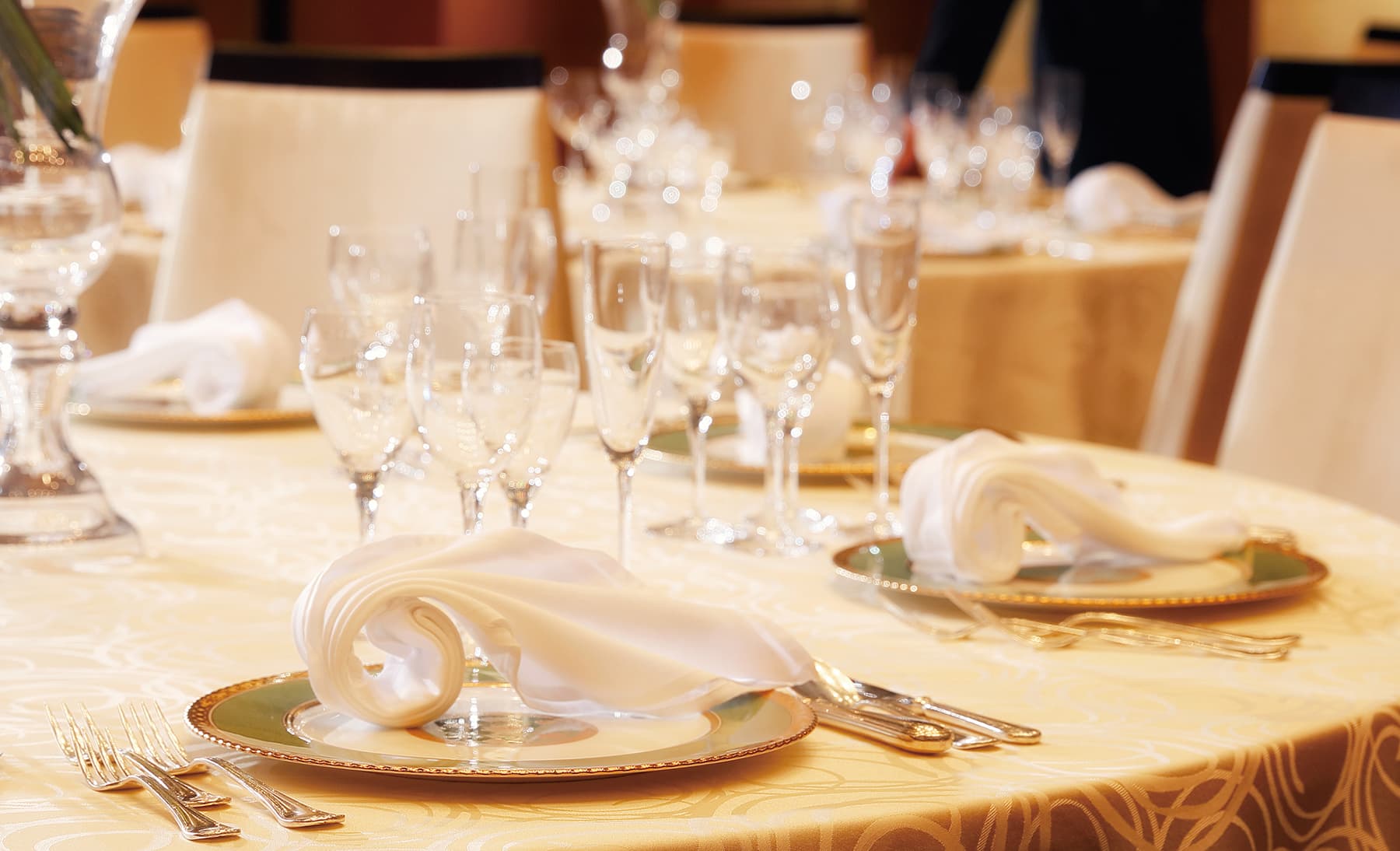 ホテルでのテーブルセッティング。ナプキンと食器が用意された宴会場の様子。