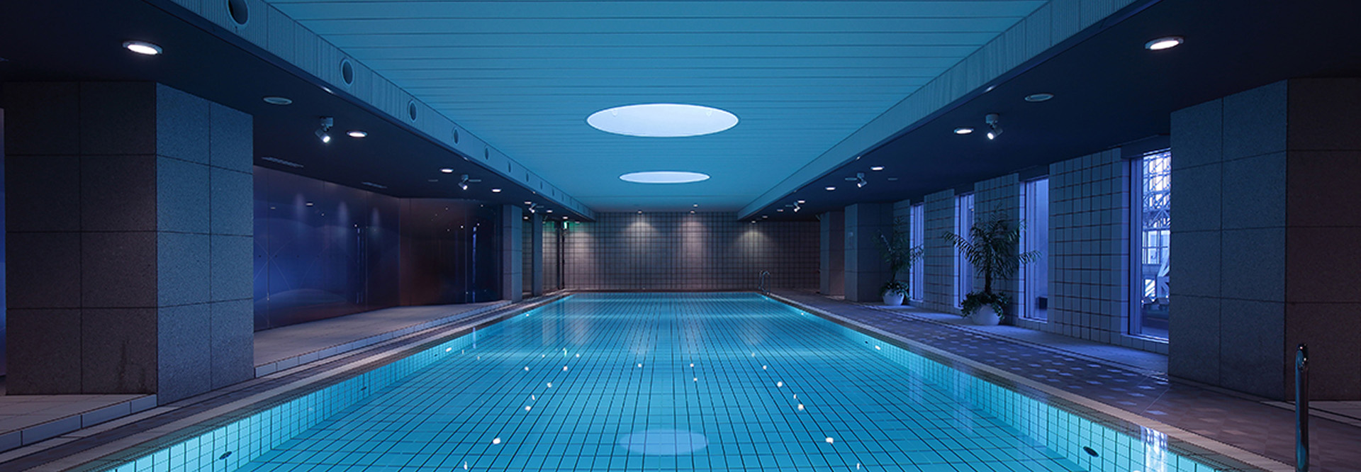 青い光に包まれた、神秘的で落ち着いた雰囲気の屋内プール。