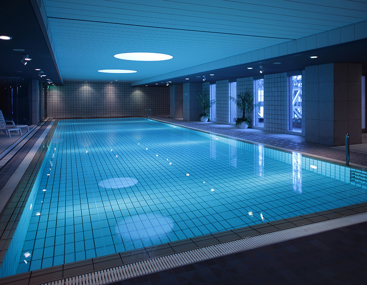 天井の丸いライトがプールの水面に反射している、静かで幻想的な雰囲気の屋内プール。
