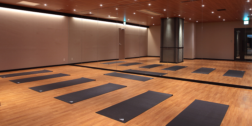 広々としたグループスタジオ。ヨガマットが整然と並び、壁一面の大きな鏡が開放的な空間を演出している。