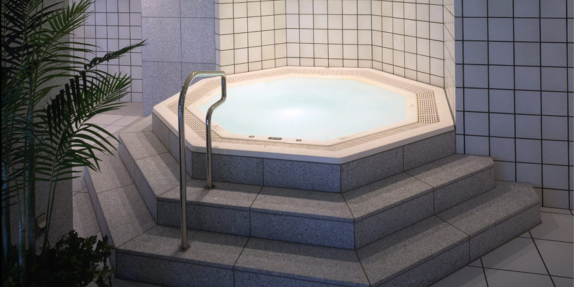 豪華でモダンなジャグジー。八角形の白い浴槽と、御影石の階段が落ち着いた雰囲気を醸し出している。