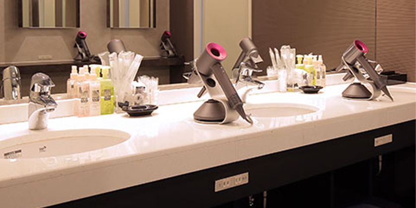 清潔で広々とした洗面台。鏡張りの壁と落ち着いた照明が、リラックスできる空間を演出している。