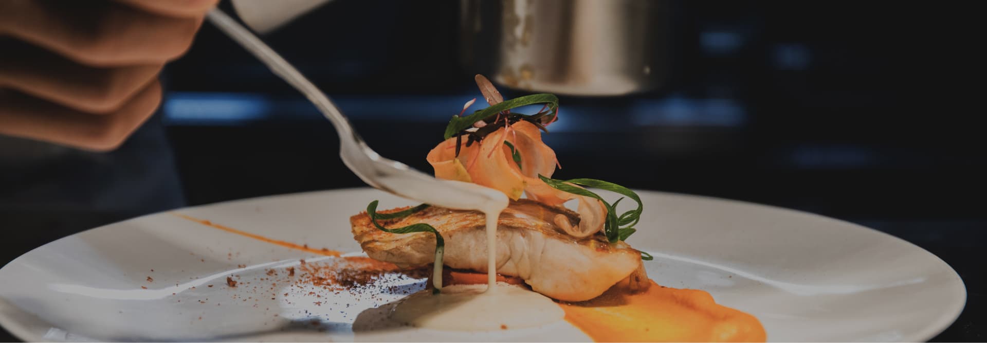シェフの手によって丁寧に仕上げられる繊細な魚料理。鮮やかなオレンジのピューレと白いソースのコントラストが美しい一皿。