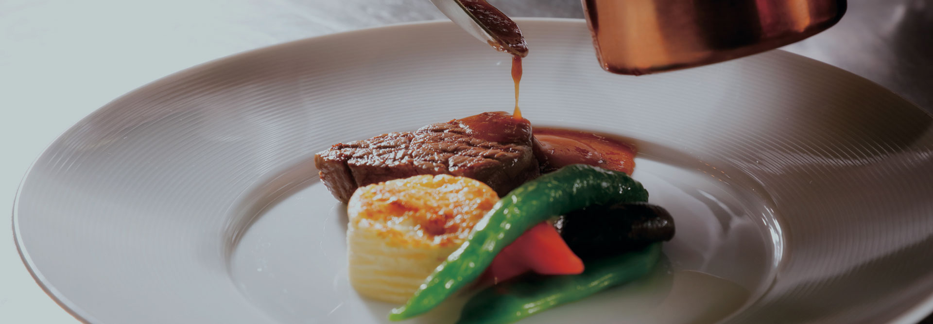 ステーキに温かいソースをかけたメインディッシュ。焼き野菜添え。