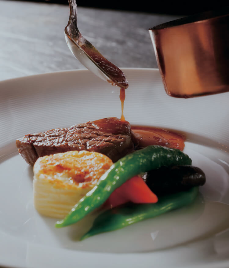 ステーキに温かいソースをかけたメインディッシュ。焼き野菜添え。