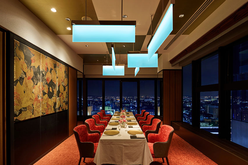 夜景を望むレストランの個室。赤い椅子とモダンな照明が特徴的な内装。