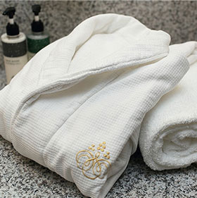 刺繍入りの白いタオルとバスローブのアメニティセット