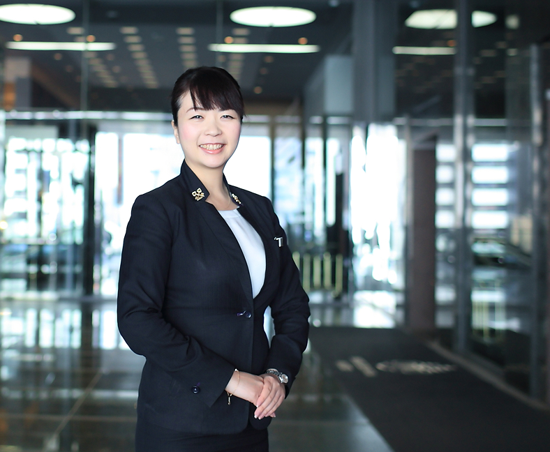 ホテルのロビーで微笑む制服姿のコンシェルジュスタッフが正面に立っている。