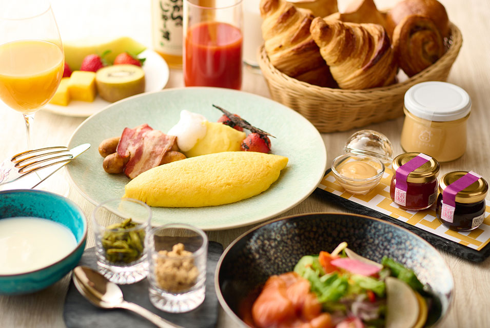 彩り豊かな洋朝食。オムレツ、サラダ、フルーツ、クロワッサン、ヨーグルト、ジュースが並んでいる。