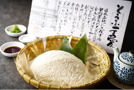 ざるに乗せられたよせ豆腐。奥には豆腐の説明書きと、しょうゆや薬味などが並べられている。