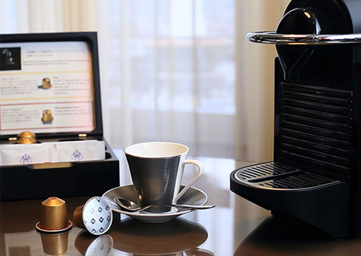コーヒーカップ＆カップソーサーのセットに添えられたコーヒーカプセルと、コーヒーマシン