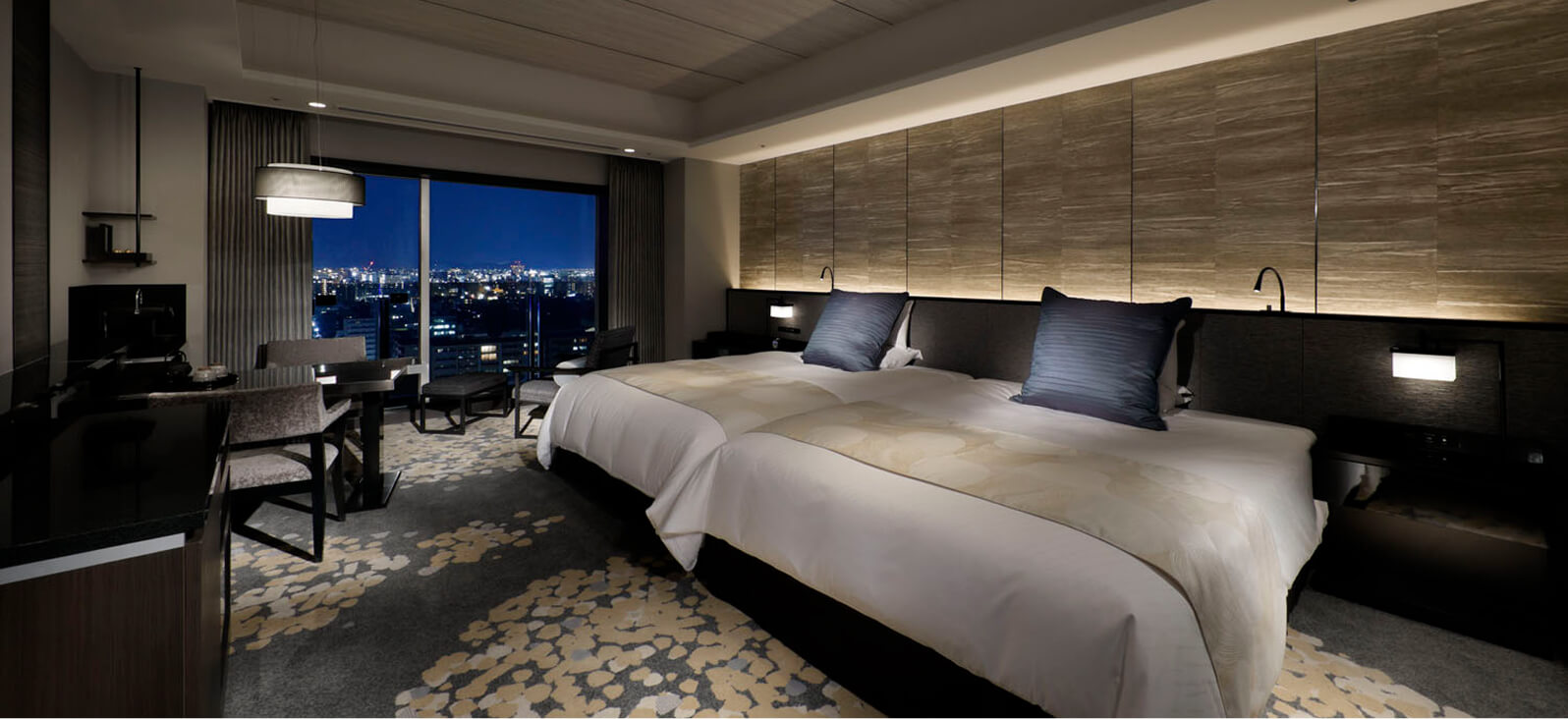 夜景を望む大きな窓と広めのベッドがあるモダンな客室