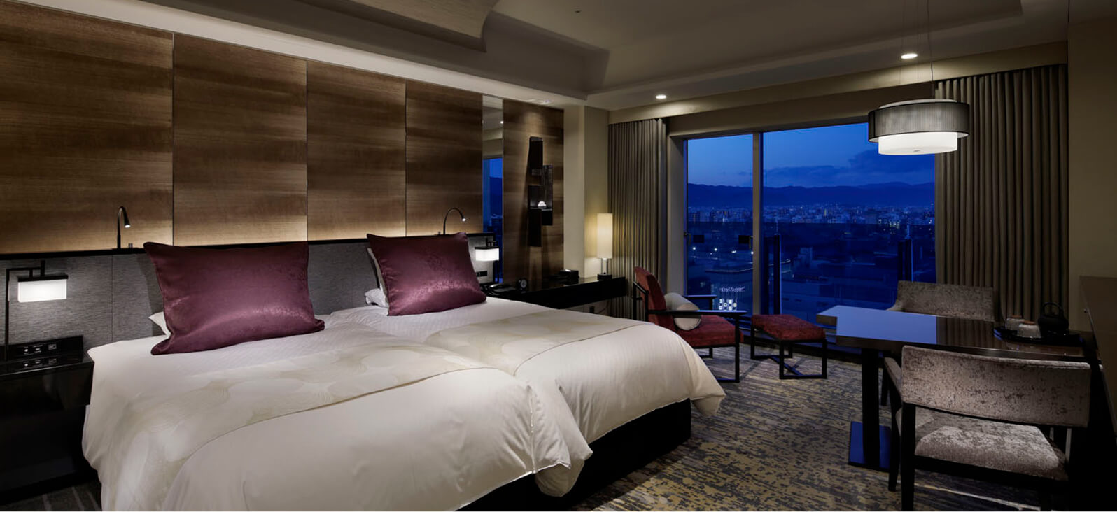 紫色のクッションがアクセントの、夜景が見えるツインベッドルーム