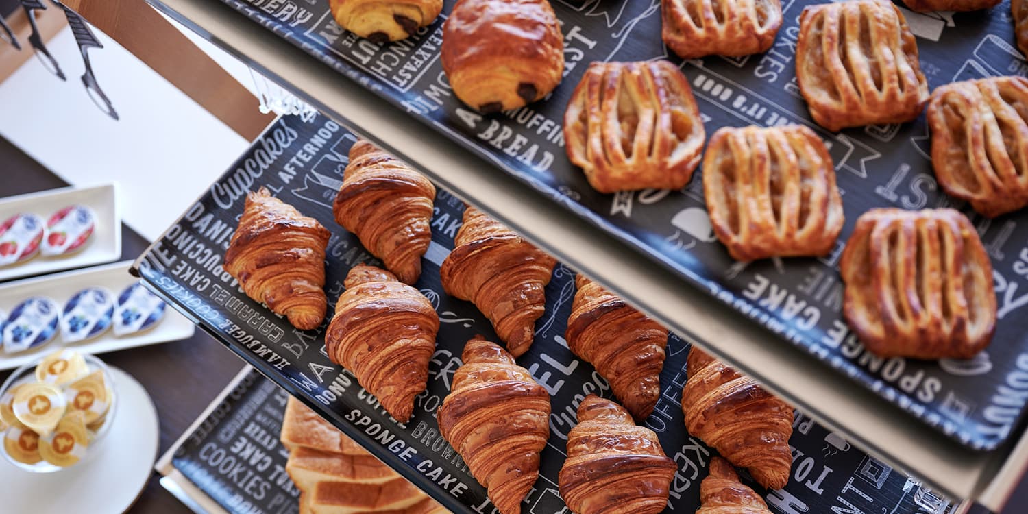 2段のトレイに並べられたクロワッサンやデニッシュなど、焼き立ての様々な種類のパン。