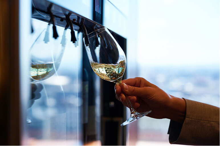 ワインサーバーからグラスに注がれている白ワインまたはスパークリングワイン。