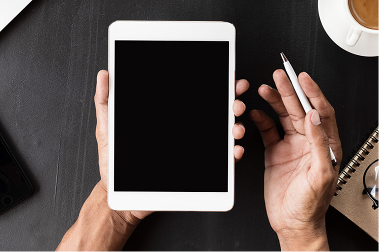 手が空白の白いタブレットを持ち、もう一方の手に白いペンを持っている様子。