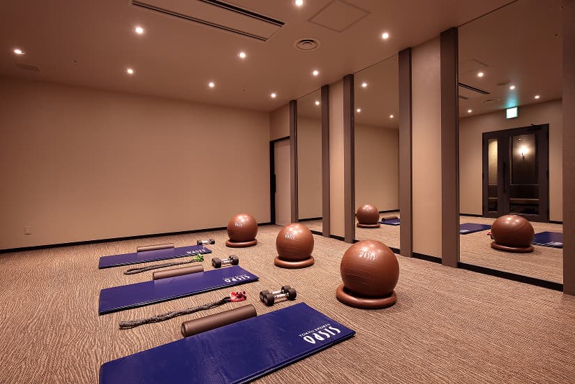 ヨガマットやバランスボール、ダンベルなどが設置された、鏡張りのスタジオ（エクササイズルーム）。