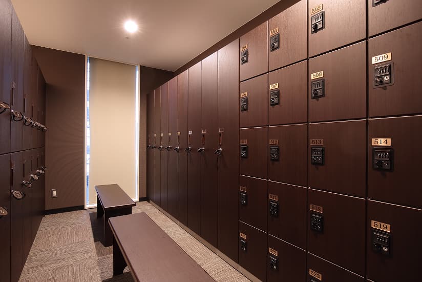 鍵付きのロッカーが壁一面に並び、ベンチが設置されたロッカールーム。