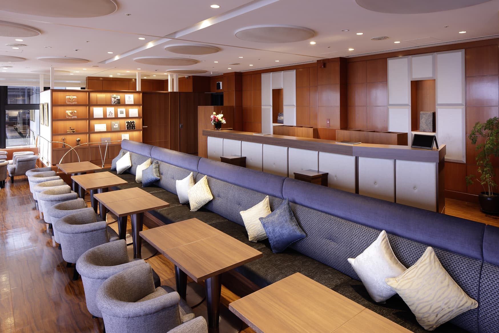 長いソファー席とカウンターが特徴的な、広々としたラウンジまたは受付スペース。