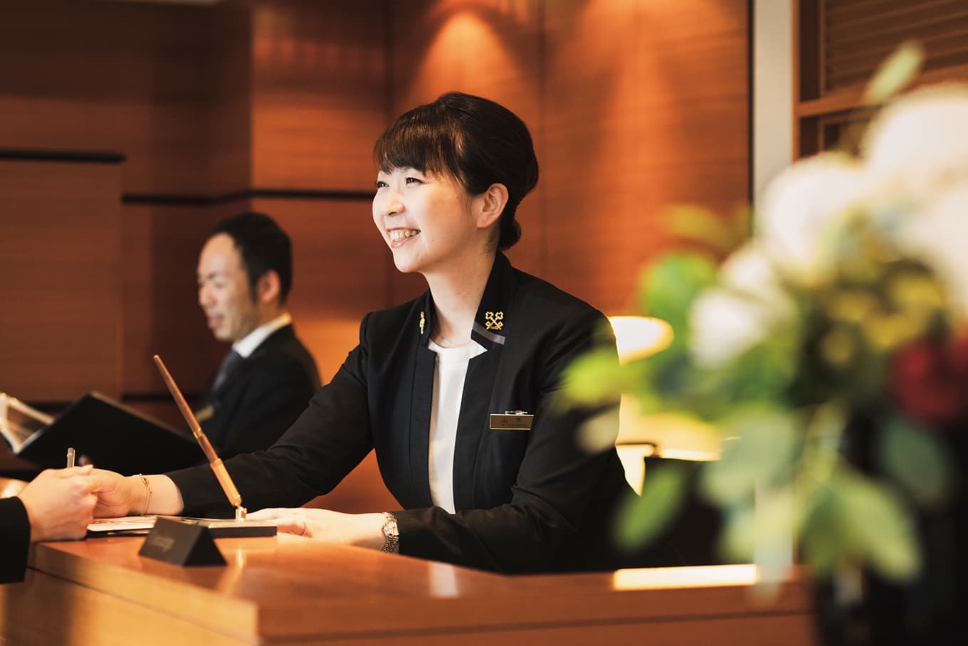 笑顔で丁寧にお客様を迎えるホテルのフロントスタッフ。