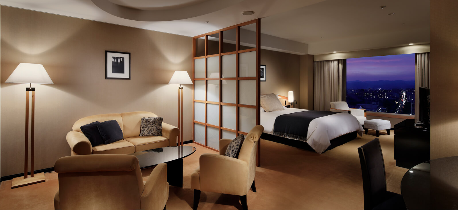 ダブルベッドとソファ、テレビがある温かみのある室内