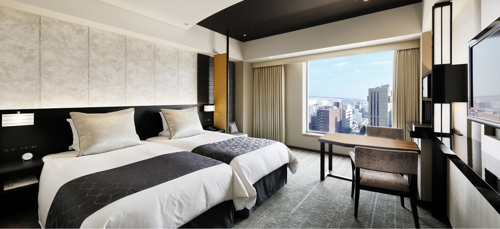 大きな窓から市街地を望める、ナチュラルトーンのツインルーム