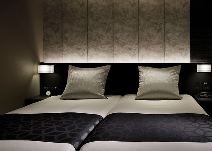 落ち着いた照明のモダンなツインルーム、黒のベッドカバー