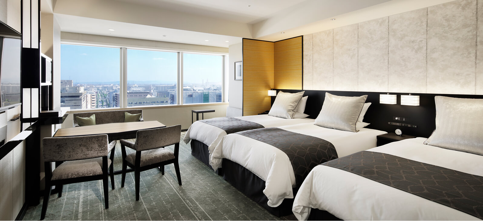 大きな窓から港や街並みが望める、ベッド3台とテーブル＆チェアを備えた明るく上品なトリプルルーム